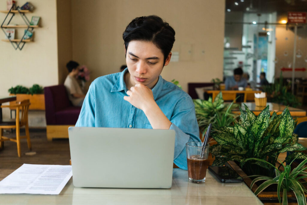 A man checking in front of laptop in cafe
