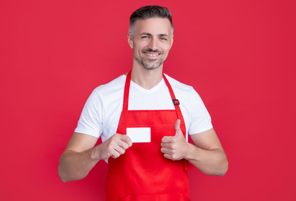 A man wearing appron holding a card