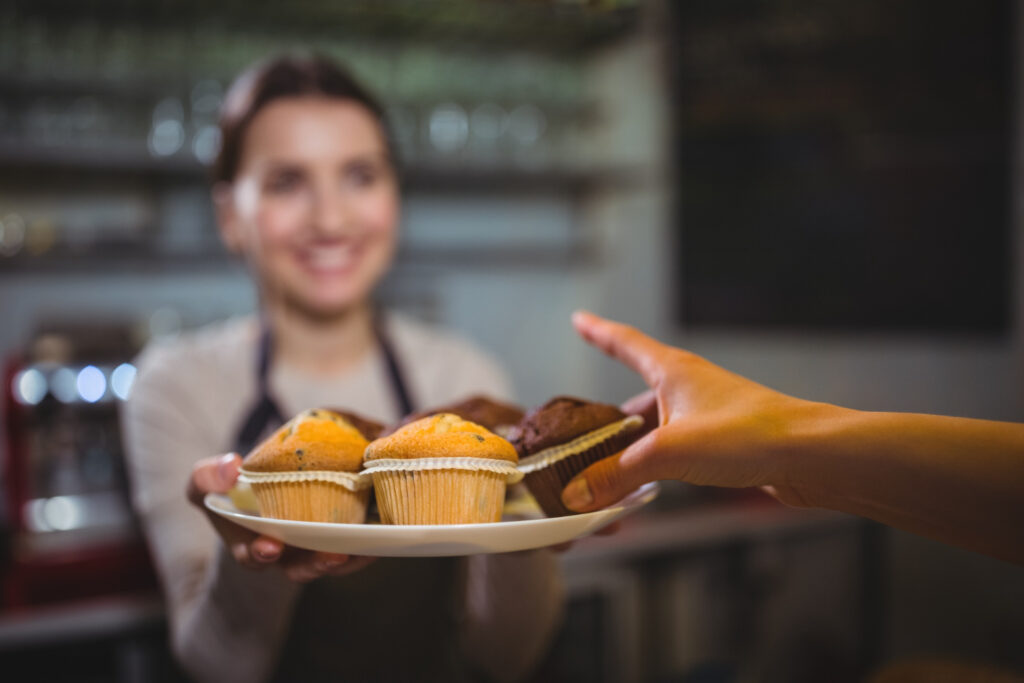 A restaurant staff offering cupcakes