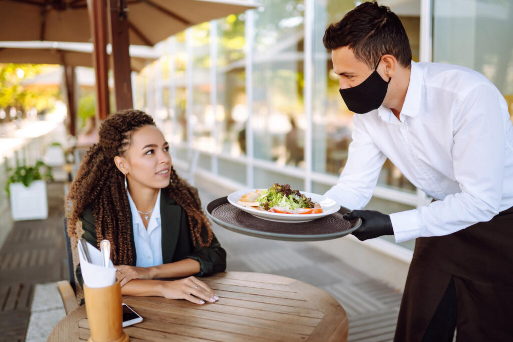A staff serving food for customer in restaurant