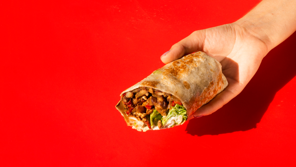 Close-up woman holding burrito with copy-space